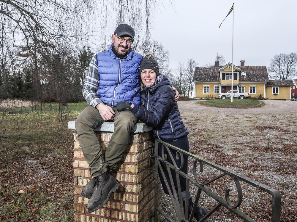 Ett par sitter på ett staket framför sin gård